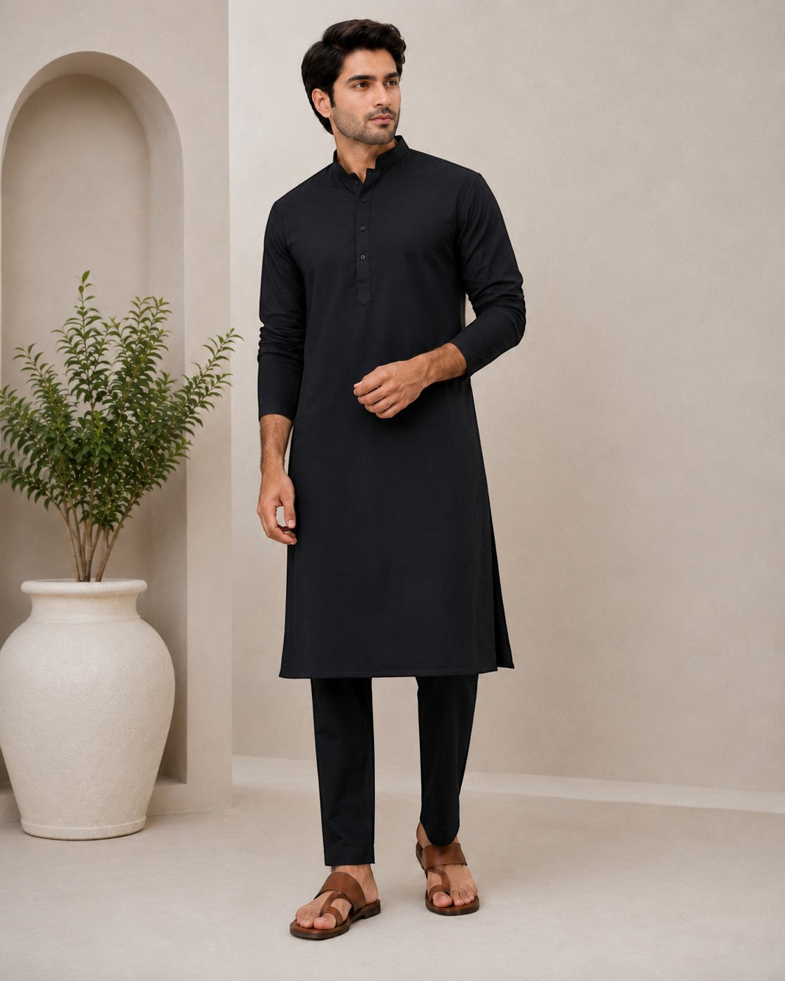 Man wearing a black cotton blend Swagzaar kurta with a mandarin collar, paired with matching trousers and sandals.